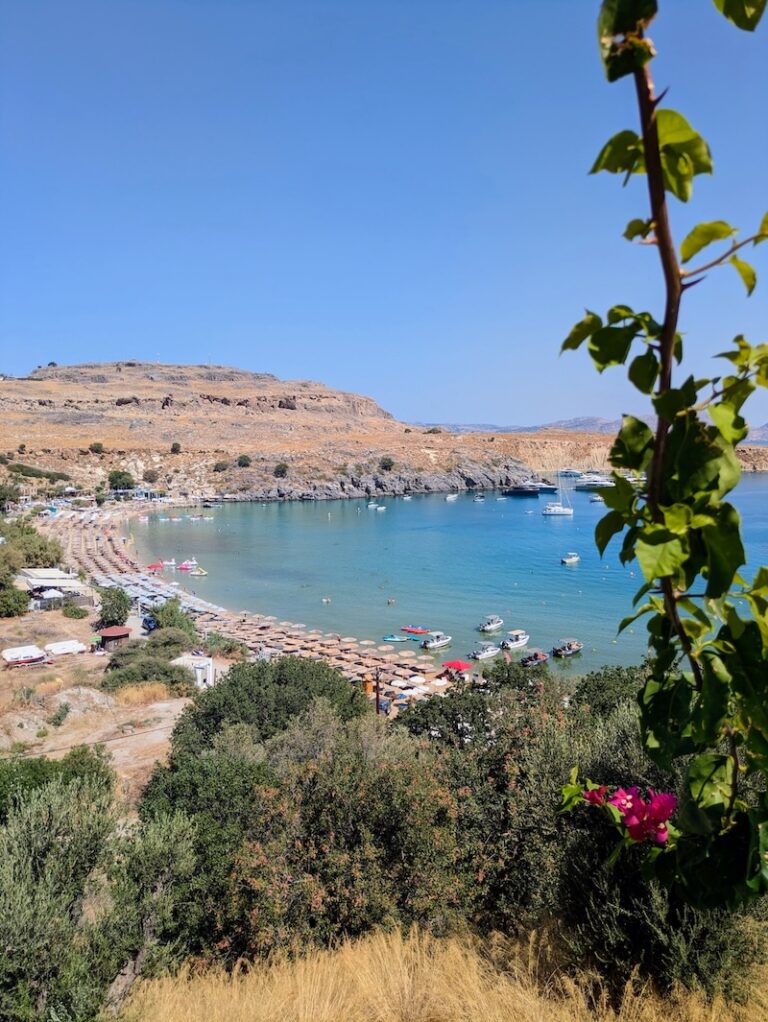 Sunbeds and parasols lining the sandy bay at Lindos Beach, Rhodes