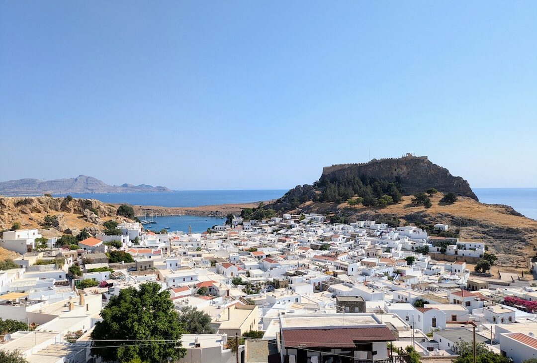 Whitewashed houses and terracotta roofs of Lindos village below the Acropolis cliff